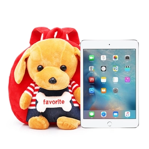 Red plush dog backpack for kids with denim overalls displayed next to a tablet