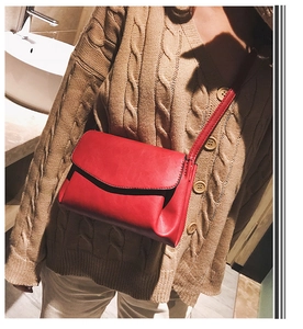 Close-up of red PU leather crossbody bag worn on shoulder with minimalist rectangular flap