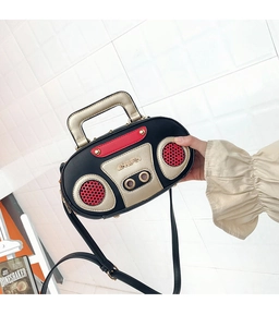Dettaglio di una borsa creativa a forma di radio con borchie e manico in metallo dorato
