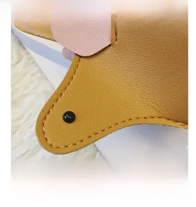 Détail du sac dinosaure pour enfant en cuir jaune avec une décoration d'oreille rose