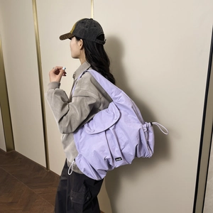Purple large capacity crossbody tote bag with drawstring detail shown on a model