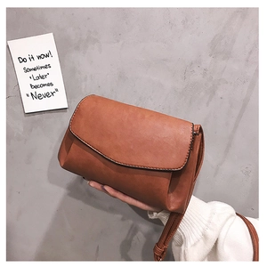Detail of caramel faux leather crossbody bag with soft pleats and textured finish