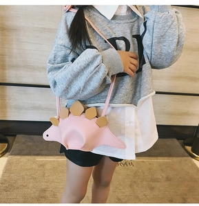 Sac bandoulière dinosaure rose pour enfant porté par un petit en intérieur cosy