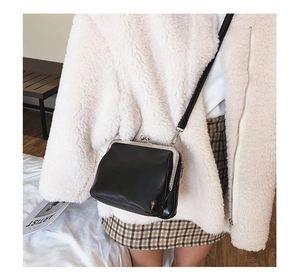 Detail of vintage black kiss lock crossbody bag paired with a winter fluffy coat outfit