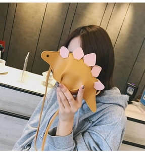 Détail d'un sac bandoulière dinosaure jaune avec des pointes roses pour enfants