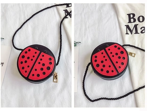 Détail d'un sac bandoulière coccinelle avec pois rouges et noirs et fermeture éclair dorée