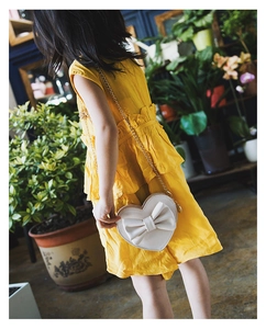 Detail of cream heart-shaped kids crossbody bag with bow and gold chain strap