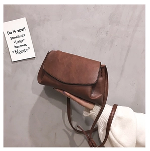 Detailed shot of vintage dark brown faux leather crossbody bag with minimalist flap design
