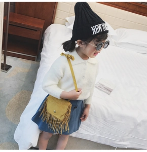 Detail of yellow fringed shoulder bag for kids with suede texture and boho tassels