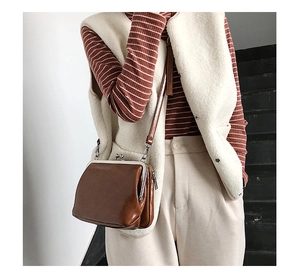 Close-up of brown vintage leather kiss-lock bag with side zipper and slim shoulder strap