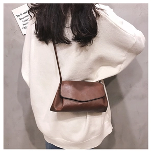 Close-up of retro brown PU leather crossbody bag paired with a white sweater