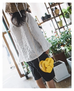 Detail of yellow heart-shaped kids crossbody bag with bow and golden chain strap