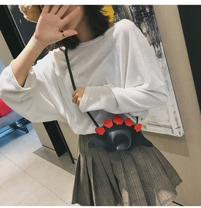 Détail d'un sac bandoulière dinosaure pour enfants avec pointes rouges et cuir noir élégant