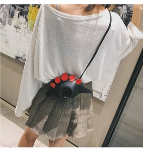 Détail du sac bandoulière dinosaure en cuir noir avec des plaques rouges pour enfants