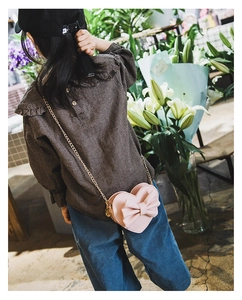 Detail showing a girl wearing a pink heart-shaped bag with a cute bow and gold chain strap