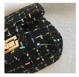 Close-up of black tweed fabric texture and golden rectangular clasp on girl handbag