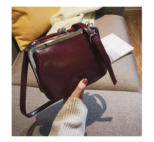 Detail of burgundy vintage kiss-lock handbag in oily wax leather with shoulder strap