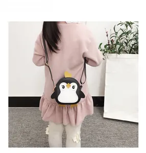 Detail shot of a cute penguin-shaped kids crossbody bag worn with a pink dress