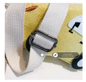 Close-up of adjustable woven shoulder strap with metal buckle on yellow corduroy bag