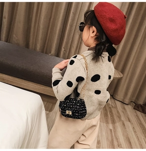 Detail of girls grey polka dot knit sweater and black tweed chain bag accessory