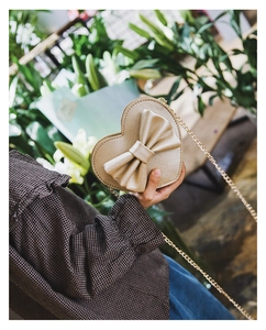 Detail of champagne gold heart-shaped crossbody bag with a large decorative bow