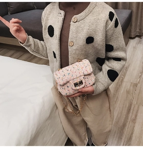 Girl wearing pink tweed crossbody bag with gold chain and metal twist lock detail