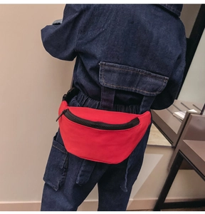 Rear view of a red nylon waist bag on a model showing the adjustable strap and buckle