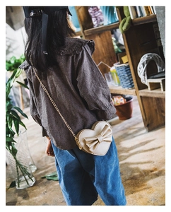 Kids heart crossbody bag with large bow and gold chain strap shown on a model