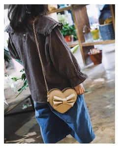 Kids heart crossbody bag with bow detail and gold chain strap shown on model
