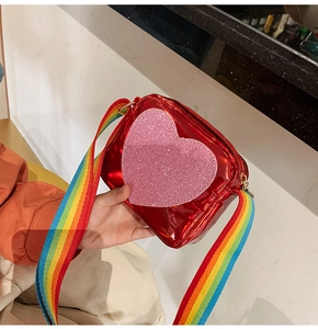 Detail of red patent leather kid's crossbody bag with glitter pink heart and rainbow strap