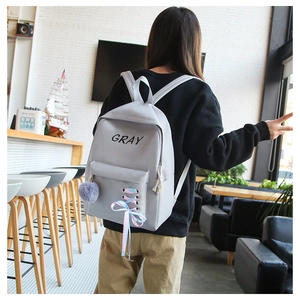 Détail du sac à dos en toile grise avec laçage en ruban coloré et pompon en peluche doux