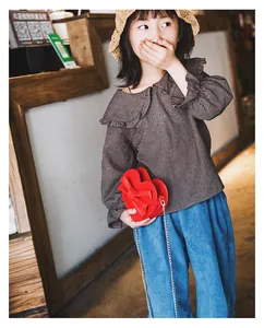 Detailed view of red heart-shaped crossbody bag with bow on a girl's stylish outfit