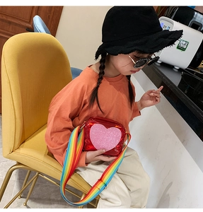 Detail of red patent leather kids bag with pink glitter heart and rainbow strap