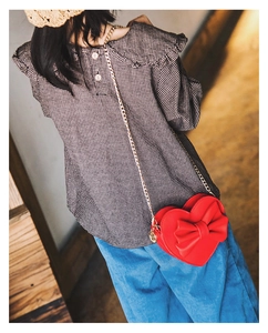 Detail view of a cute red heart-shaped kids crossbody bag with a large bow and gold chain