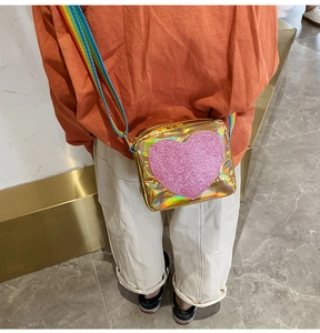 Close-up of golden laser heart crossbody bag with colorful rainbow shoulder strap
