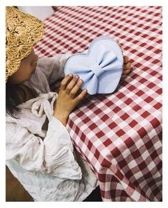Detail of light blue heart-shaped bag with large bow and gold chain strap