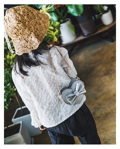 Close-up of heart-shaped silver kids crossbody bag with bow and gold chain strap