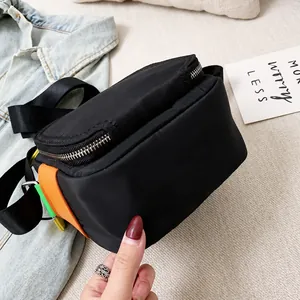 Detailed view of the black crossbody bag showing stitching and orange-green patch design