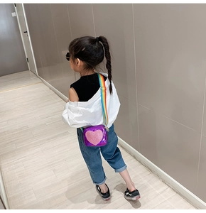 Detail of purple laser patent leather heart bag with rainbow strap on a young model