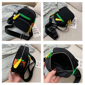 Detail view of black nylon crossbody bag with vibrant neon colored zipper pulls