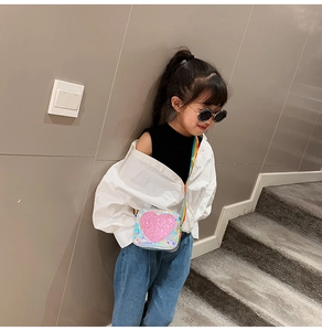 Girl wearing shiny silver laser crossbody bag with pink glitter heart and rainbow strap