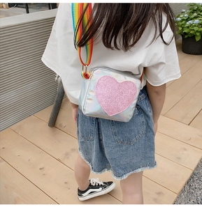 Girl wearing heart laser crossbody bag with rainbow strap on a sunny terrace