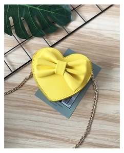 Detail of yellow heart-shaped crossbody bag with a large bow and gold metal chain