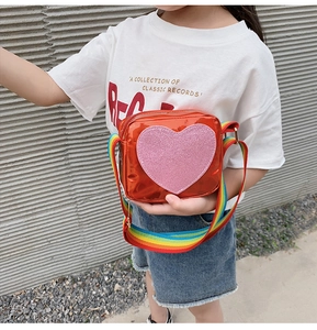 Girl's orange laser heart crossbody bag with rainbow strap shown on model