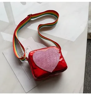 Detail of red shiny leather kids bag with pink sequin heart and rainbow strap