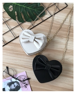 Detail of cute heart-shaped crossbody bags with large bows and golden chain straps