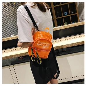 Détail d'un mini sac à dos en PVC orange transparent avec texte imprimé blanc mode