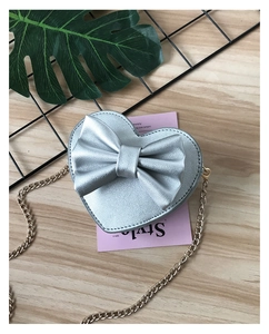 Detail of silver heart-shaped kids crossbody bag with large bow and gold chain strap