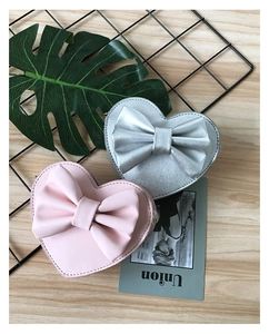 Detail of pink and silver heart-shaped PU leather bags with bow knots and zipper closures