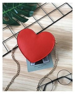 Detailed view of a red heart-shaped leather mini bag with a fine gold chain strap